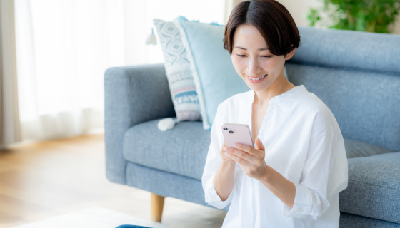 家でスマホを使って電話予約している女性の様子
